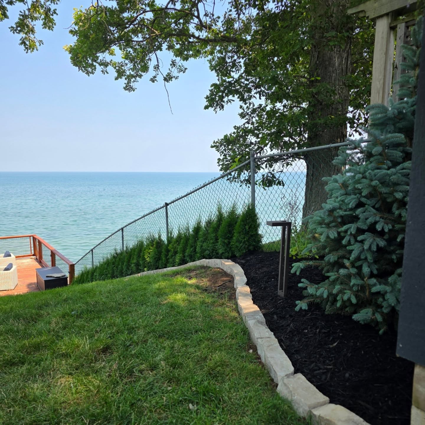 Recently finished mulch bed with stone edging along a lakefront yard